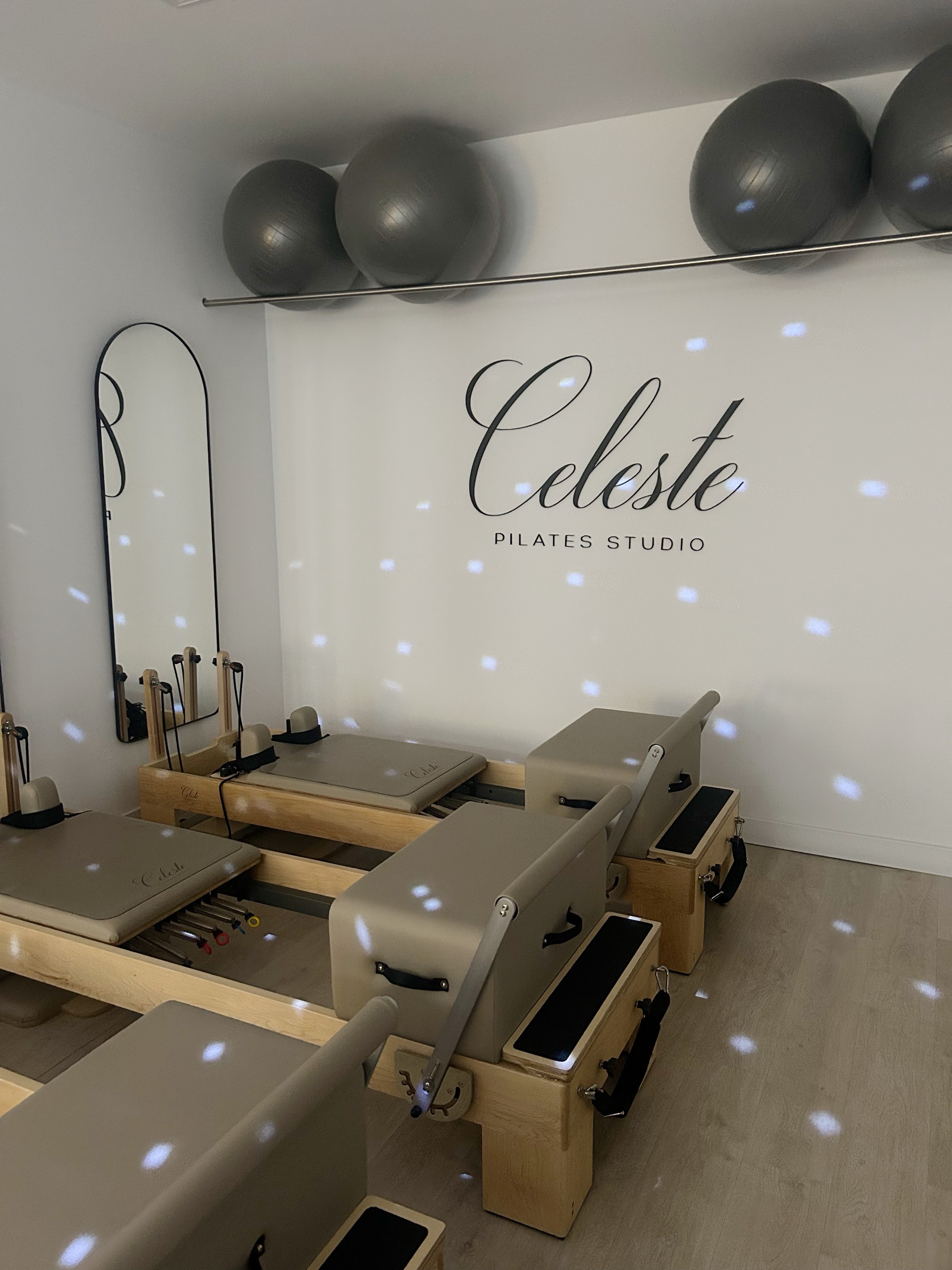 La sala de Celeste con sus reformers, espejos y reflejos de luz sobre la pared con el logotipo
